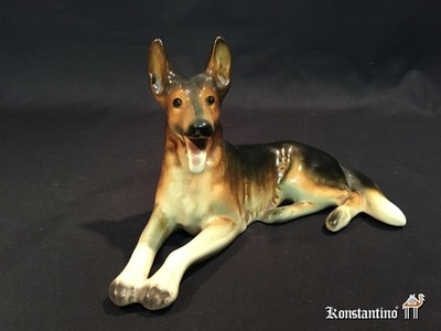1053-C 19 cms   Figura en porcelana policromada alemana de Perro Pastor alemán. s.XX
